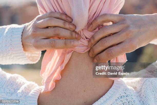 close up view of a woman with cancer tying a pink scarf on her head outdoors. - fight for life imagens e fotografias de stock