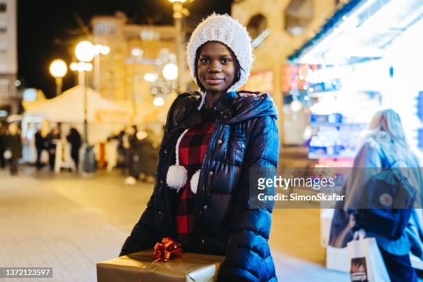 portrait of african american woman holding christmas gift - zagreb night stock pictures, royalty-free photos & images