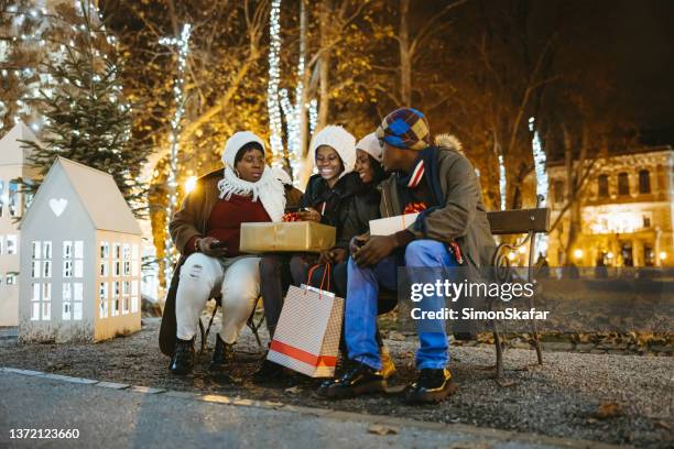 family using mobile phone sitting on bench while during christmas - zagreb night stock pictures, royalty-free photos & images