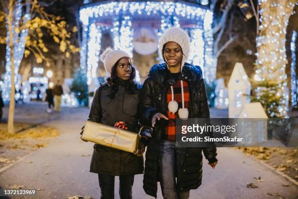 sisters walking on street with gift during christmas - zagreb night stock pictures, royalty-free photos & images