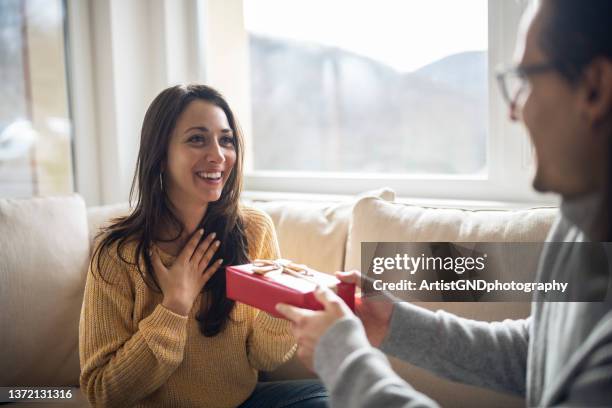 cheerful young woman receiving a gift from her boyfriend. - passing giving stockfoto's en -beelden