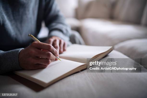 cropped hand of man writing in notebook. - poetry stockfoto's en -beelden