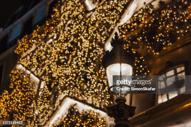 old street light in paris with lighting, hundreds of christmas light bulbs in the background - paris christmas stock pictures, royalty-free photos & images
