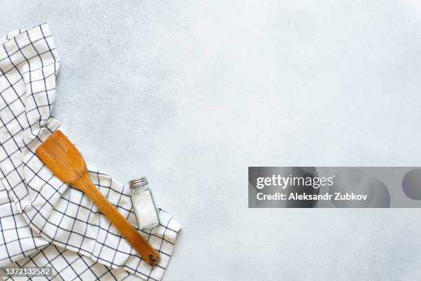 a new clean wooden spatula, a kitchen towel and a salt shaker on the dining table. the concept of cooking in a restaurant and cafe, at home in the kitchen. cook it yourself, taking courses on the ability to cook delicious and beautiful food. copy space. - salt shaker fotografías e imágenes de stock