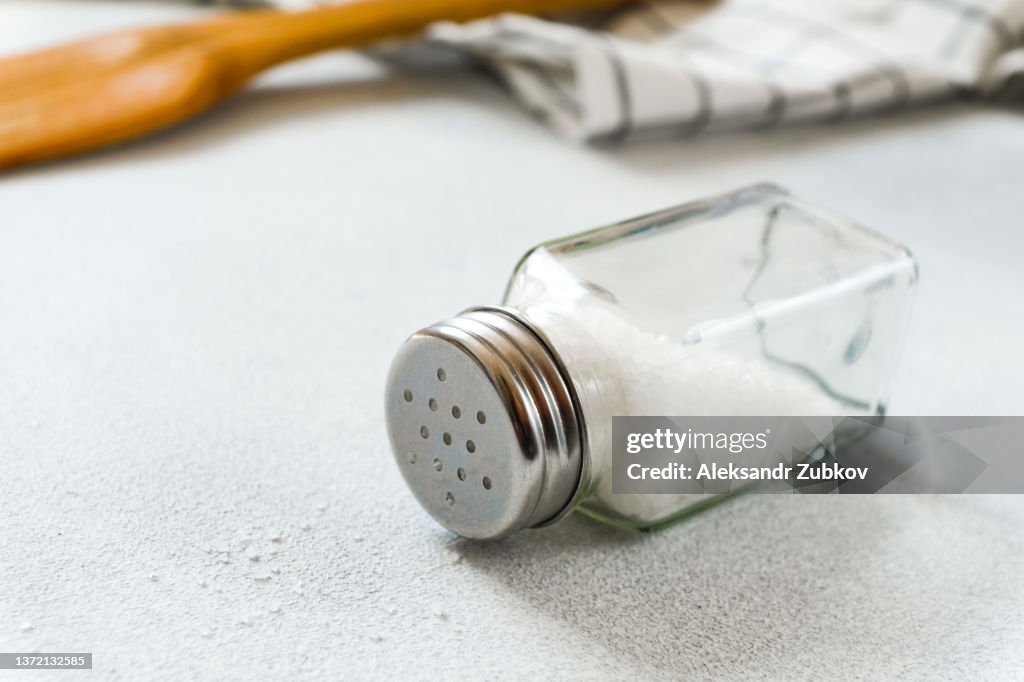 A new clean Wooden spatula, a kitchen towel and a salt shaker on the dining table. The concept of cooking in a restaurant and cafe, at home in the kitchen. Cook it yourself, taking courses on the ability to cook delicious and beautiful food. Copy space.