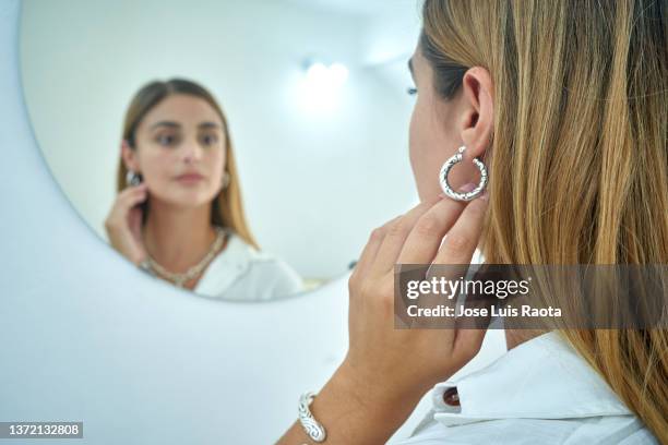 woman deciding between two sets of earrings - ear piercing stock pictures, royalty-free photos & images