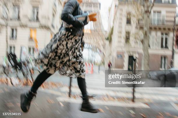 französin hat es eilig, trägt zwei baguettes und rennt den bürgersteig vor dem eiffelturm in paris entlang - running paris stock-fotos und bilder