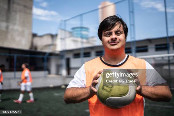 porträt eines jungen männlichen fußballspielers mit besonderen bedürfnissen auf einem sportplatz - amateur stock-fotos und bilder