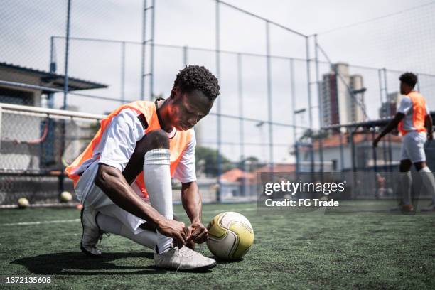 player tie his shoes on the soccer field - soccer boot stock pictures, royalty-free photos & images