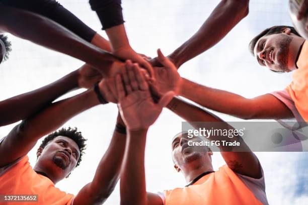 players stacking hands together on the soccer field - community effort stock pictures, royalty-free photos & images