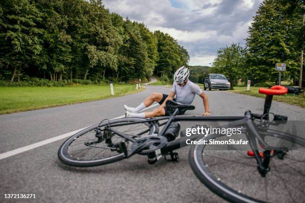 injured cyclist sitting in pain on the road - bicycle crash stock pictures, royalty-free photos & images