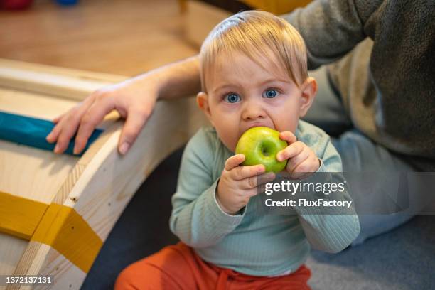 süßes kleinkind junge, der in den apfel beißt - baby spielt mit essen stock-fotos und bilder