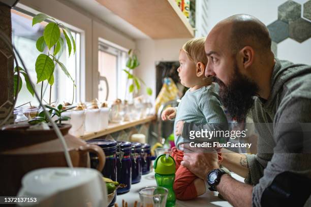 padre e hijo mirando a través de la ventana de la cocina - baby powder fotografías e imágenes de stock