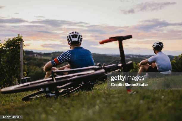 cyclists sitting and enjoying the view in the vineyard at sunset - finishing workout stock pictures, royalty-free photos & images