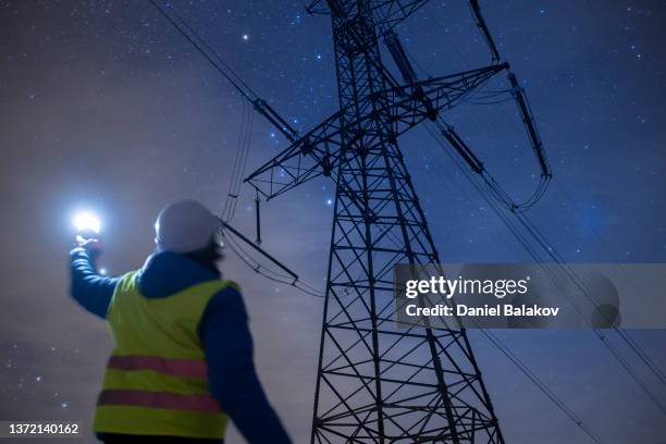 ingeniero de alta tensión trabajando de noche en el campo. energía sostenible. - cable de conducción eléctrica fotografías e imágenes de stock