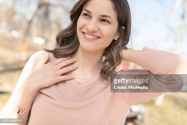portrait of a happy, beautiful woman putting on the silver necklace - diamond necklace stock pictures, royalty-free photos & images