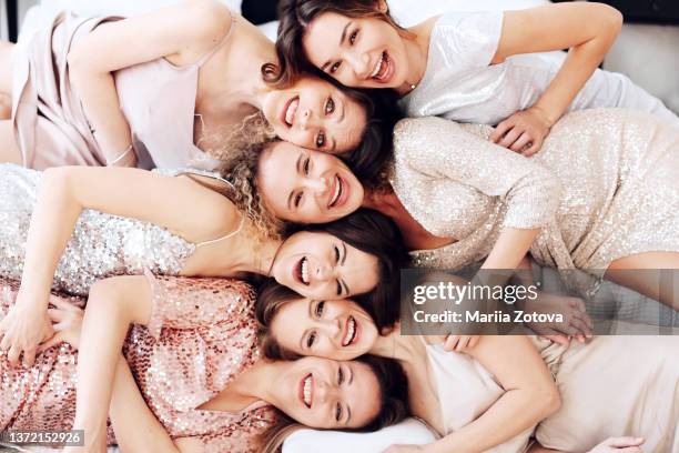 a group of beautiful women in dresses smile, celebrate and raise a toast and have fun together. girls ' party - smile woman child stockfoto's en -beelden