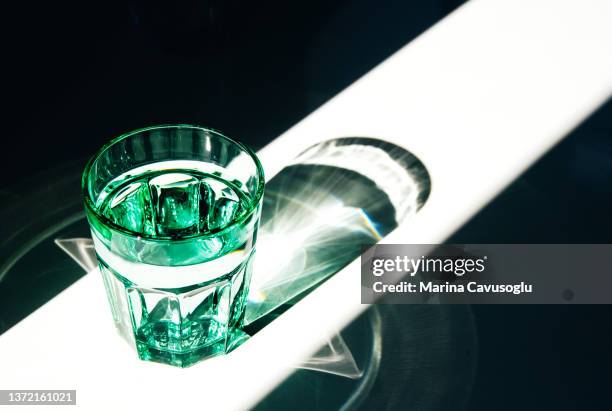 green glass of water. sunlight, shadows and reflections. - glass shadow stockfoto's en -beelden