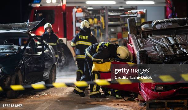 firefighters at a car accident scene - motor vehicle accident injury stock pictures, royalty-free photos & images