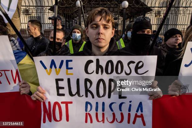 People hold signs and chant slogans during a protest outside the Russian Embassy on February 22, 2022 in Kyiv, Ukraine. After Russian forces...
