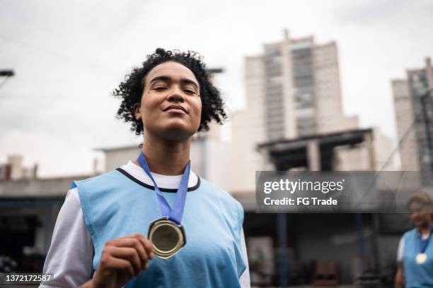 retrato de una jugadora de fútbol celebrando ganar una medalla - showing off fotografías e imágenes de stock