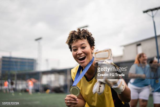 portrait of a female soccer player celebrating winning a medal - sportsperson medal stock pictures, royalty-free photos & images