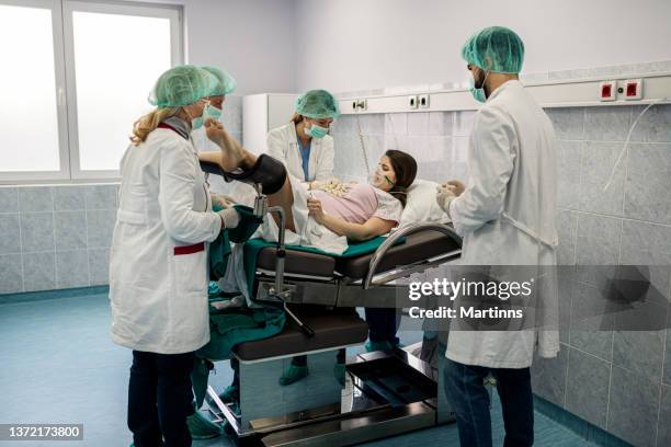 obstetricians assisting in the hospital woman in labor pushes to give birth - maternity ward stock pictures, royalty-free photos & images