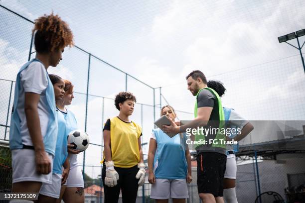 coach and female soccer players planning a game - team sport huddle stock pictures, royalty-free photos & images