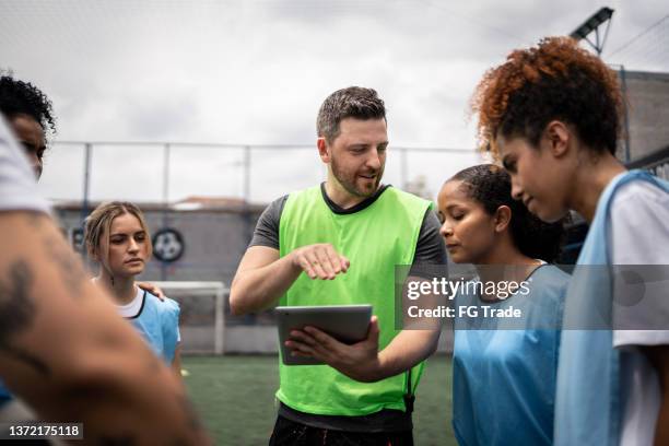 coach and female soccer players planning a game - sport tablet stockfoto's en -beelden