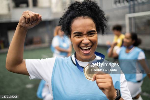 portrait of a female soccer player celebrating winning a medal - real life hero stock pictures, royalty-free photos & images