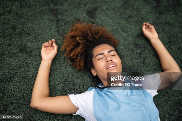 exhausted female soccer player - lying down stockfoto's en -beelden