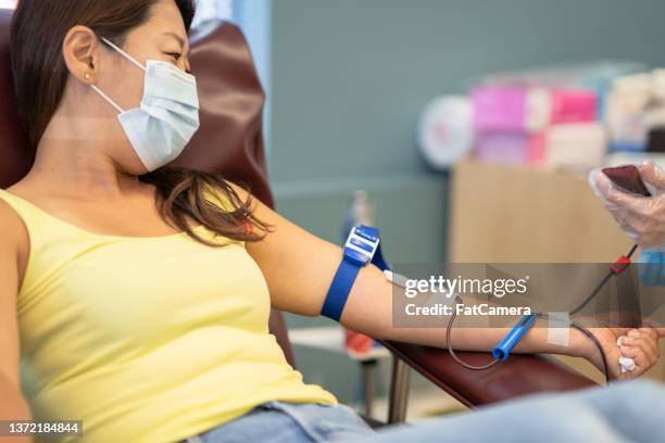 woman having her iv placed for blood donation - tourniquet stock pictures, royalty-free photos & images