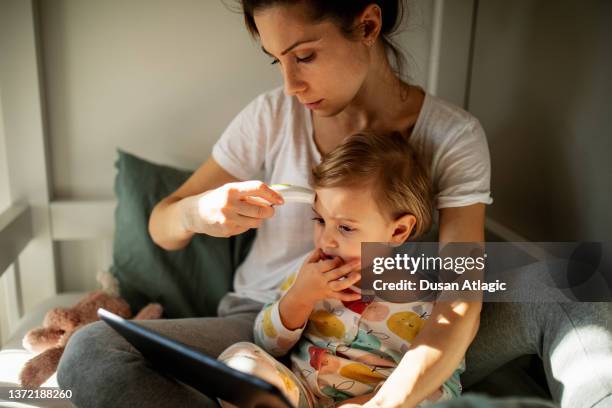 mother taking care of sick child - digital thermometer stock pictures, royalty-free photos & images