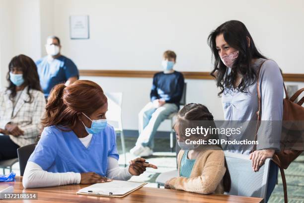 krankenschwester zeigt auf den jungen patienten - vaccination center stock-fotos und bilder