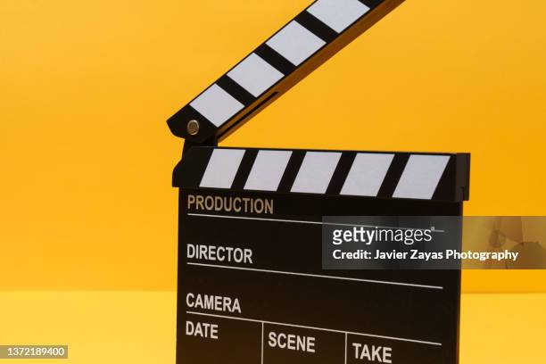 clapper board on yellow background - movie still stock-fotos und bilder