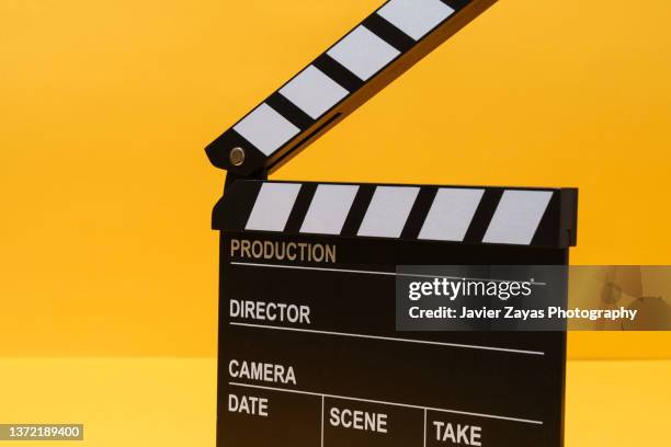 clapper board on yellow background - film stockfoto's en -beelden