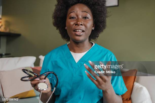 porträt einer ärztin, die bei einem videoanruf mit patientin spricht - webcam stock-fotos und bilder