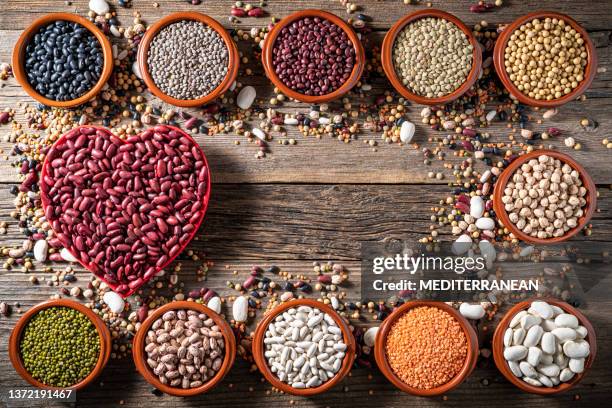 legumbres variadas en cuencos de cerámica con corazón rojo sobre marco de fondo de madera rústica con legumbres mixtas - red bean fotografías e imágenes de stock