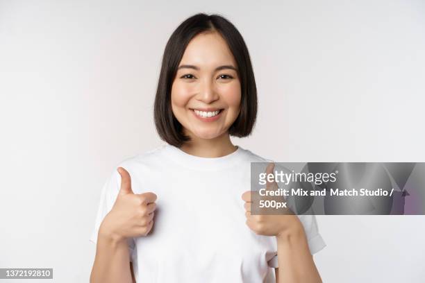 happy young korean woman showing thumbs up and smiling,give positive - happy woman thumbs studio ストックフォトと画像