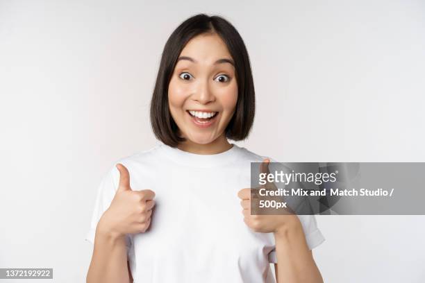 happy young korean woman showing thumbs up and smiling,give positive - happy woman thumbs studio ストックフォトと画像
