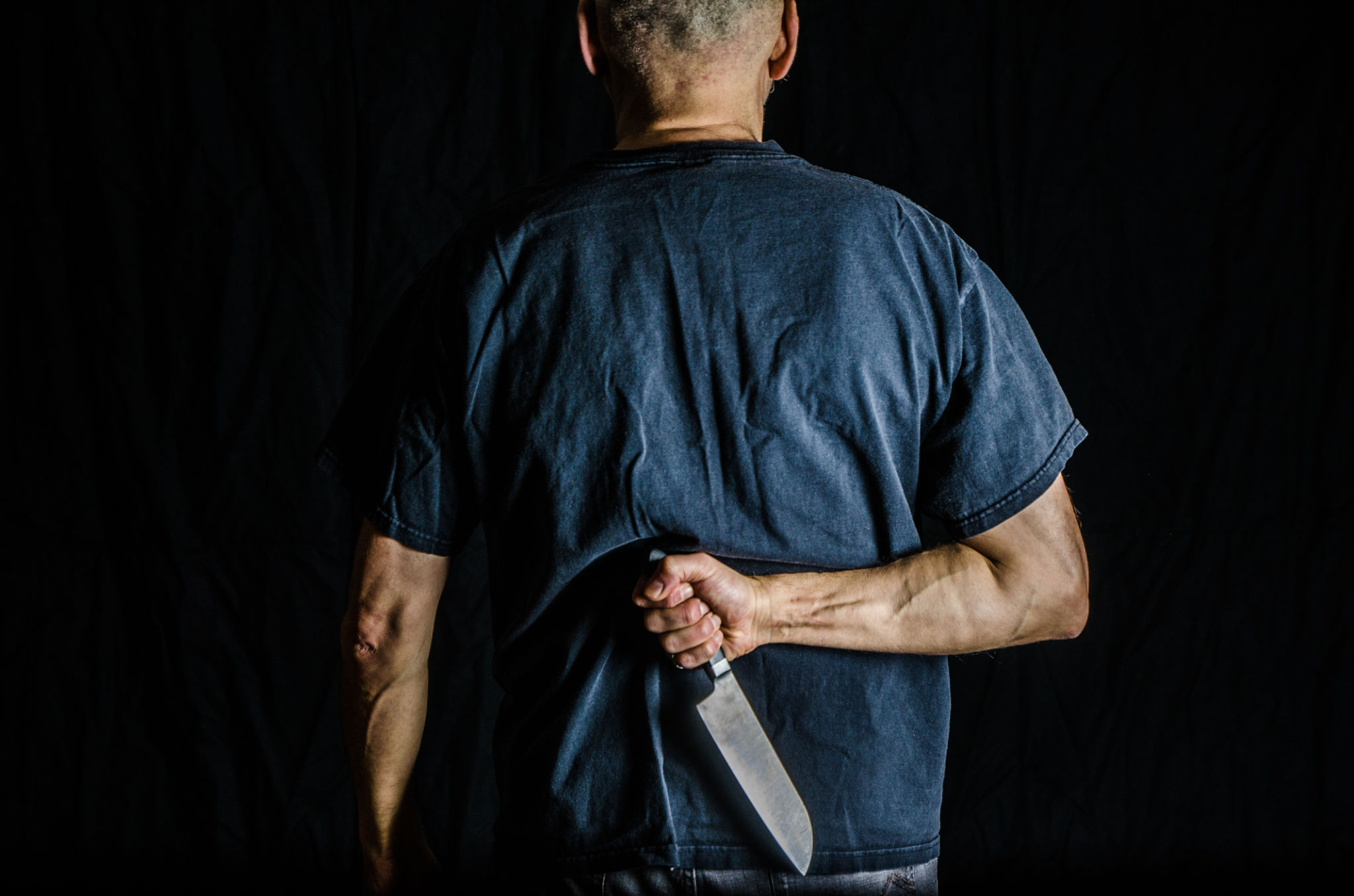 Man holding kitchen knife in his back Man holding kitchen knife in his back