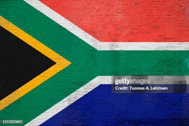 full frame photo of a weathered flag of south africa painted on a plastered brick wall. - south african flag stock pictures, royalty-free photos & images