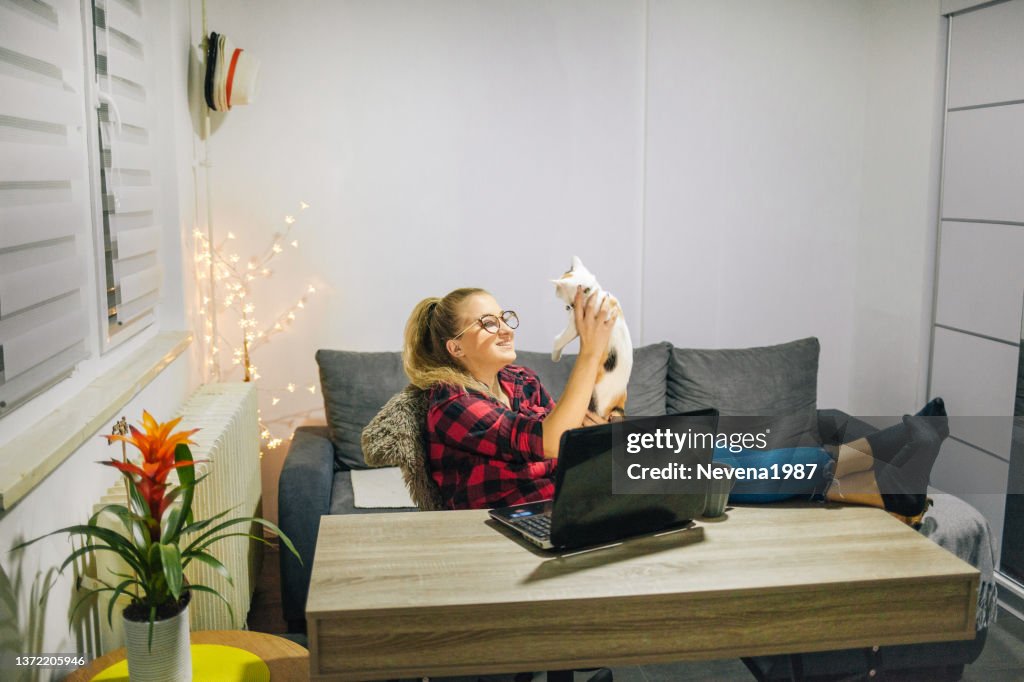 Young woman with cat and dog using laptop