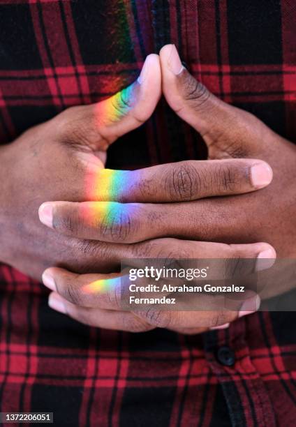 close-up of joined hands of african american with rainbow light - hands resting stock pictures, royalty-free photos & images