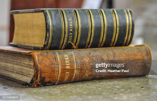 old and worn holy bible books stacked on a table - bible stock pictures, royalty-free photos & images