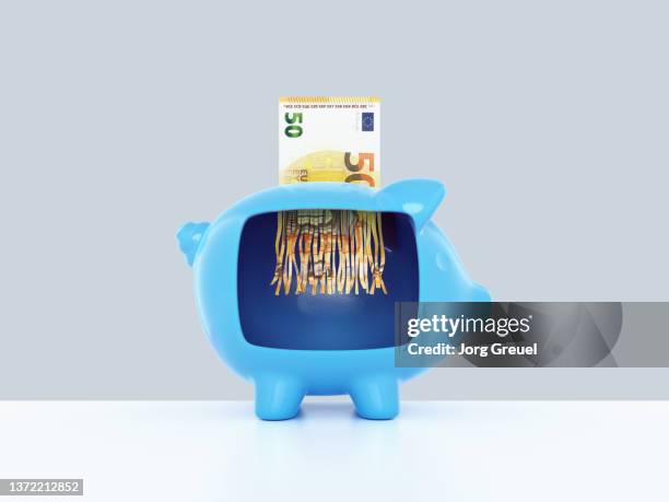 euro banknote being shreddered inside a piggy bank - inflation euro stock-fotos und bilder