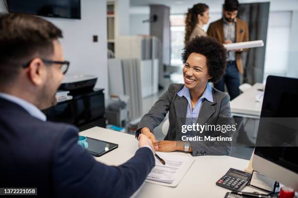 two business colleagues shaking hands after reaching an agreement for future business - dark skin stock pictures, royalty-free photos & images