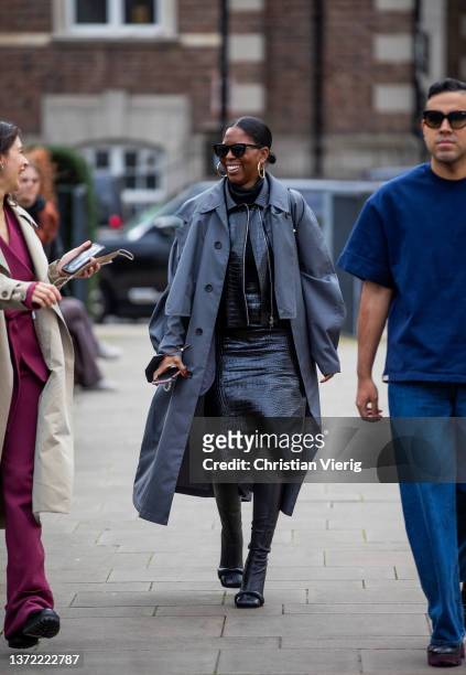 Guest is seen wearing grey coat, black vinyl dress, black knee high boots outside Roksanda during London Fashion Week February 2022 on February 21,...