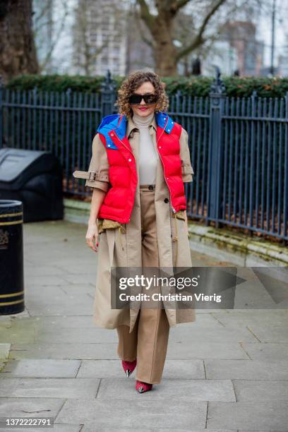 Renia Jaz seen wearing beige trench coat, red blue puffer vest, turtleneck, beige pants, red heels, red Chanel bag outside Roksanda during London...