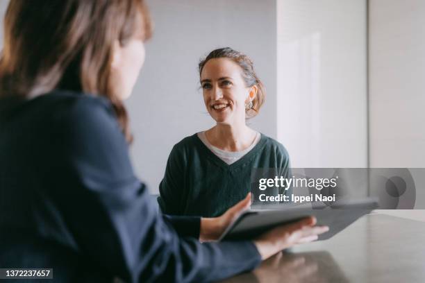 woman meeting female banker for financial advice - agente de seguros fotografías e imágenes de stock